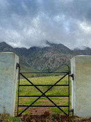 Farm gate looking up to the mountains with dark clouds above