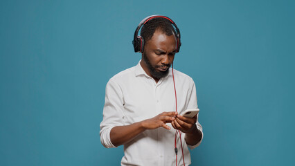 Young person listening to sound on headphones with mobile phone, paying attention to podcast....