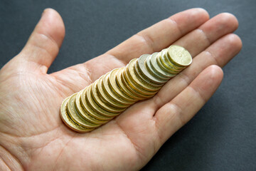 Selective focus of Turkish lira coins stacked one after the other in male hand. The coins are...