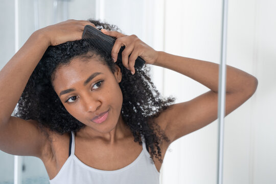 Young Black Woman Looking Her Curly Hair At Mirror