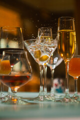 A bright modern cocktail with olives falling into a glass, splashes of water