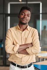 Fototapeta premium Portrait of confident young African-American marketing expert in yellow shirt standing with crossed arms