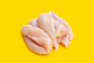 Raw chicken tenders on yellow background.