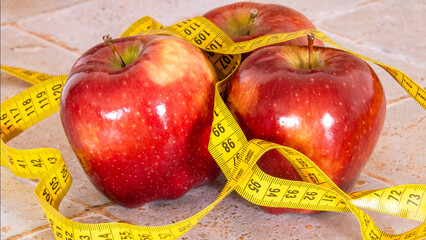 close up of several red apples isolated on a table with a measuring tape