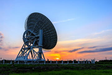 Astronomical radio telescope and beautiful sky clouds at sunset