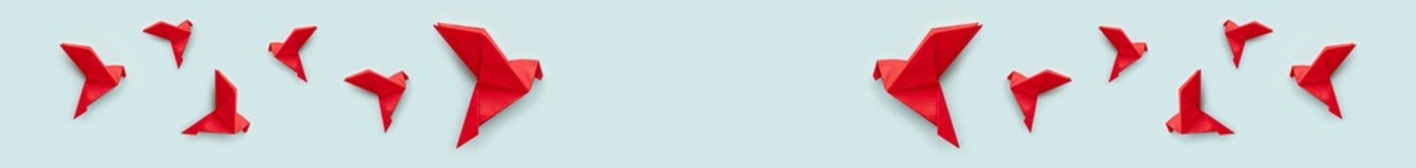 many red paper origami pigeons on pastel blue background