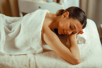 Fototapeta na wymiar Woman relaxing with eyes closed, enjoying professional massage at spa center. Resort, therapy