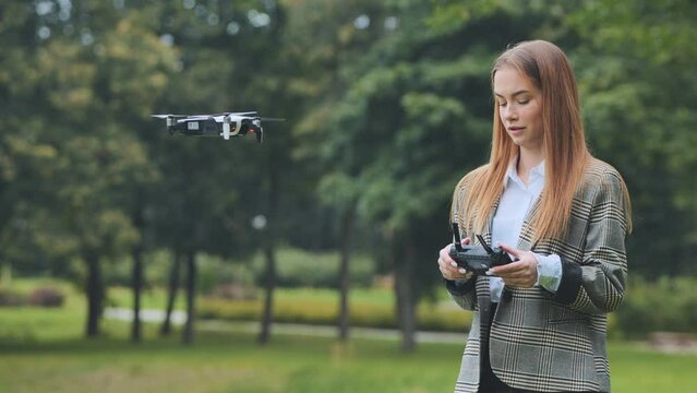 A cute girl controls a drone in the park.