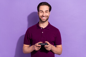 Photo of optimistic young brunet guy play station wear violet t-shirt isolated on purple color background