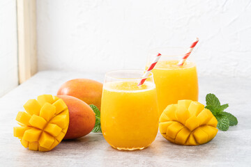 Fresh beautiful delicious mango juice smoothie in a glass cup on gray table background.