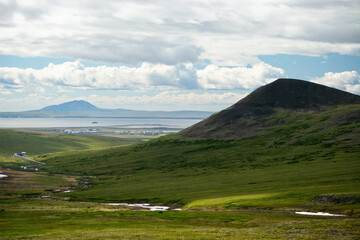 Summer Arctic landscape. View of the tundra and mountains. In the distance, the settlement of Ugolnye Kopi, Anadyr Airport and the Anadyr estuary. Chukotka, Siberia, Far East of Russia.