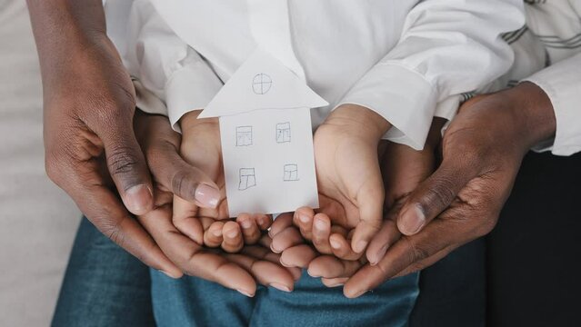 Close-up female male and child hands of african family holding cardboard shape of house picture of home dream of housing relocation renting new flat moving in together real estate insurance bank loan