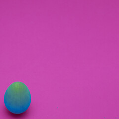 Easter colorful blue egg with copy space on a pink background. Minimal Easter composition.