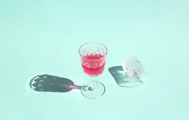 Minimal concept glass of red wine and thier shadow on sunny day. Crystal glasses on pastel green...
