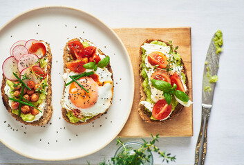 Vegetarian egg sandwiches on white background.. Healthy vegetarian sandwiches with egg tomatoes avocado cream and cheese garnished with chia seeds and aromatic herbs. Vegetarian sandwich.