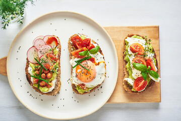 Vegetarian egg sandwiches on white background.. Healthy vegetarian sandwiches with egg tomatoes avocado cream and cheese garnished with chia seeds and aromatic herbs. Vegetarian sandwich.