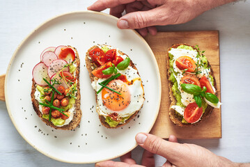 Vegetarian egg sandwiches on white background.. Healthy vegetarian sandwiches with egg tomatoes avocado cream and cheese garnished with chia seeds and aromatic herbs. Vegetarian sandwich.