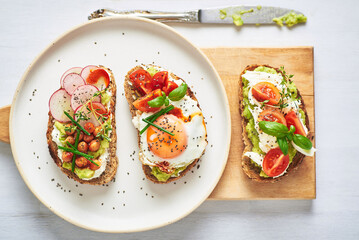 Vegetarian egg sandwiches on white background.. Healthy vegetarian sandwiches with egg tomatoes avocado cream and cheese garnished with chia seeds and aromatic herbs. Vegetarian sandwich.