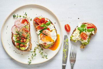 Vegetarian egg sandwiches on white background.. Healthy vegetarian sandwiches with egg tomatoes avocado cream and cheese garnished with chia seeds and aromatic herbs. Vegetarian sandwich.