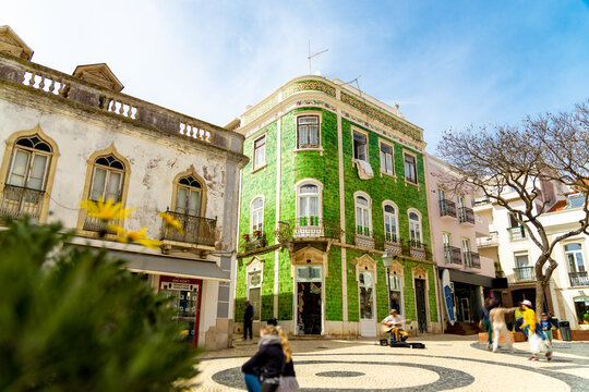 Historical town centre in Lagos, Algarve, Portugal with moving people and a green tiled building.