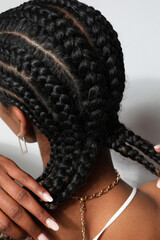 Vertical close-up of African woman with braids posing on white background.