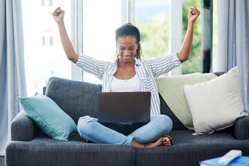 The fast wifi is working in her favor. Shot of a young woman cheering while using a laptop at home.