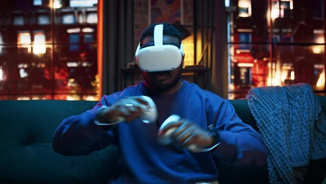Conceptual Zoom In Shot of a Young Handsome Black Man Putting On VR Headset and Getting Immersed in Virtual Reality. Creative Gamer Sitting on a Sofa at Home, Playing VR Video Games. 