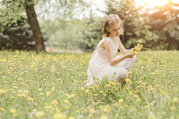 girl sniffs tulips on the lawn in a city park.