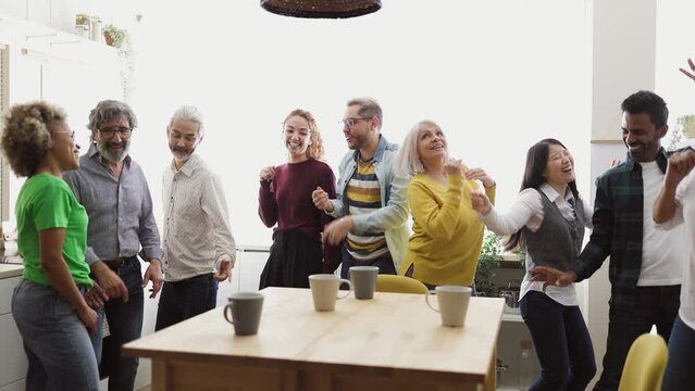 Happy multiracial people with different ages and ethnicities having fun dancing while drinking a cup of coffee at home
