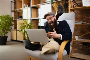 Portrait of young bearded man, happy yogi doing yoga exercise on armchair in homeoffice at work...