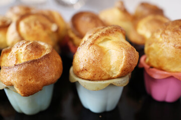 Homemade popover, which is a lush, airy and egg hollow roll, fresh from the oven. Yorkshire pudding freshly baked in silicone blue and pink baking dishes, selective focus.