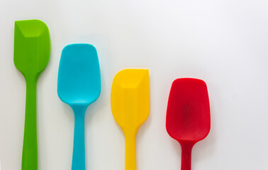 Silicone spatulas in various color, red, blue, green and yellow lay on white background