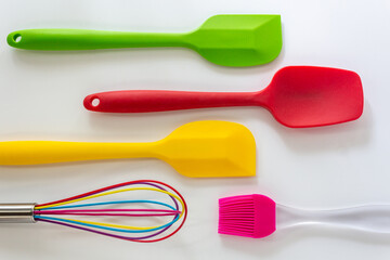 Spatulas ,whisk and cooking brush made from silicone in various color lay on white background