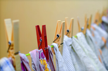 Clothes pegs on a string holding laundry - selective focus on red clip