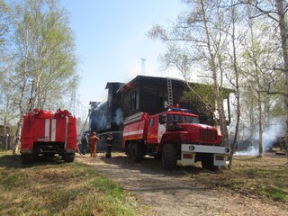 A fire truck on the background of a burning wooden house