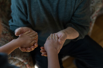 the hands of the child embracing a hand of the old man
