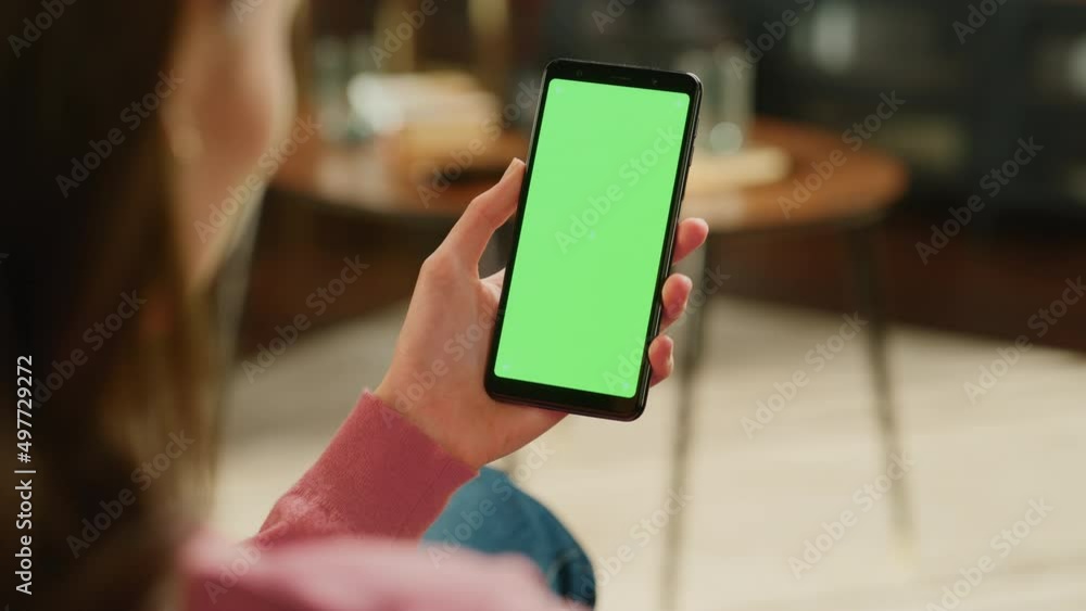 Poster Feminine Hand Tapping on Display and Scrolling Feed on Smartphone with Green Screen Mock Up Display. Female Resting at Home, Checking Social Media on Mobile Device. Close Up Over the Shoulder Footage.