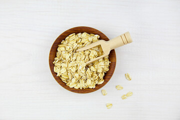 Oat flakes in a bowl on a white wooden background. Top view. 