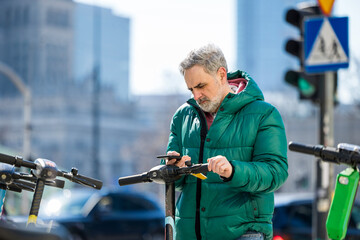 Mature man activating electric scooter from smartphone 
