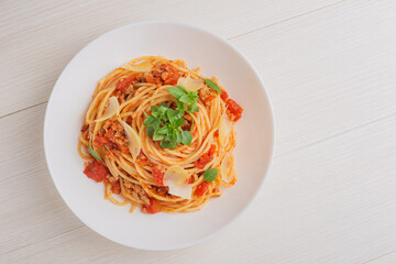 The Italian pasta spaghetti Bolognese on white plate on wooden table. Top view. Mediterranean...