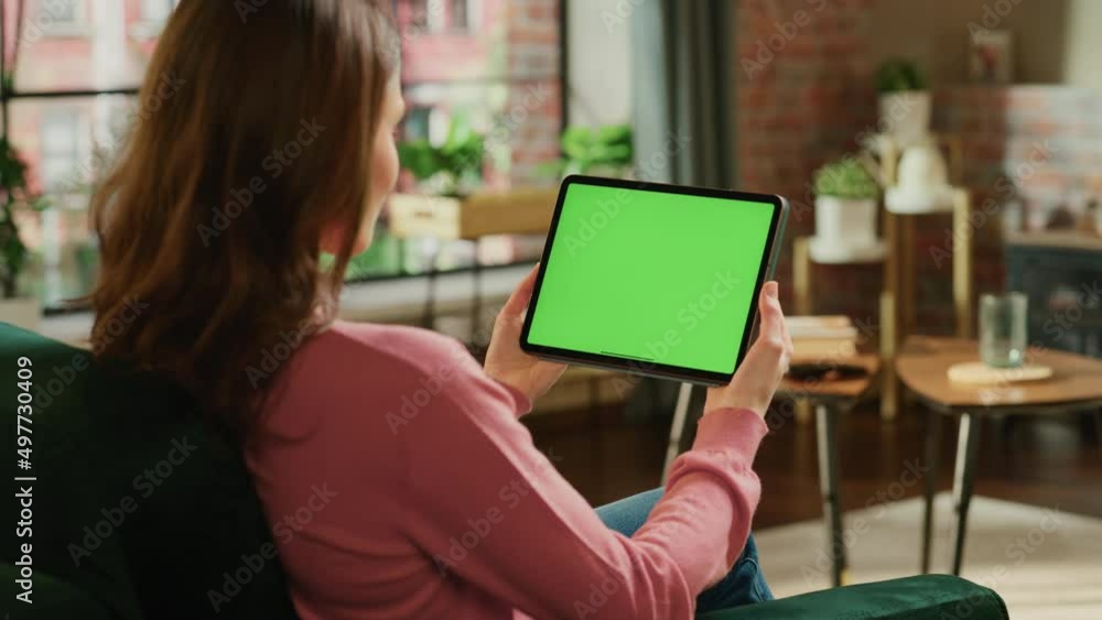 Aufkleber female holding tablet computer with green screen mock up display. woman relaxing at home, watching v
