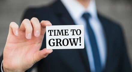 Businessman presenting 'Time to grow' word on white card