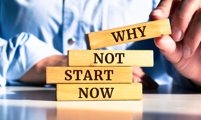 Businessman stacking wooden pegs to assemble the Why not start now sign in a conceptual image.