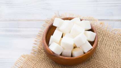 Refined sugar lies in a wooden bowl