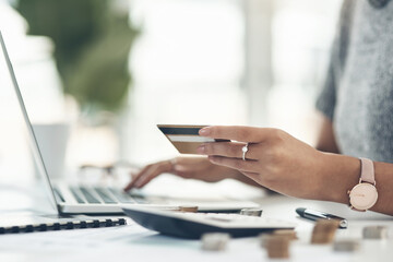 Fototapeta premium Sorting out her outstanding payments the efficient way. Closeup shot of an unrecognisable businesswoman using a laptop and credit card in an office.