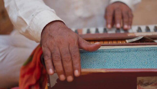 Closeup shot of Hands of an Indian street performer playing harmonium while singing at Jaisalmer in Rajasthan, India. Street performer playing harmonium in the side of the road. 