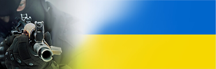 A machine gun in the hands of a Ukrainian soldier on the background of the Ukrainian flag. Blurred image, selective focus