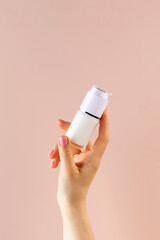 A mock-up of a jar of moisturizer in a woman's hand on a pink background.