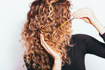 Young woman applying hair care oil