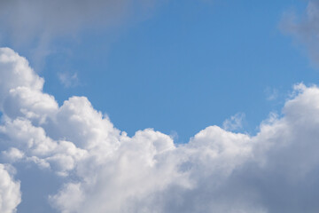 Blue sky with white clouds in sunny weather. Fluffy white cloud against a clear blue sky. Bright contrasting sky with clouds. Sky-cloud background
